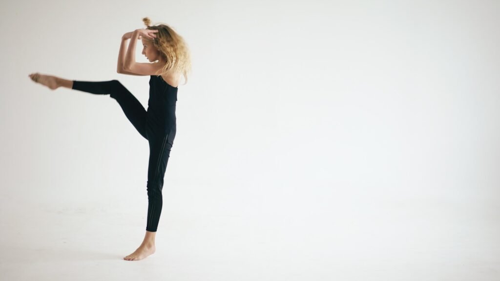 Young dancer in black leotard performs a graceful pose.