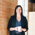 woman standing by wall holding mug